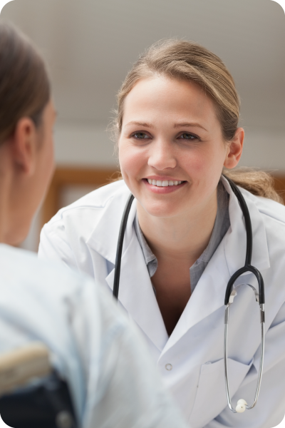 A woman with a lab coat and stethoscope leans in to talk to another person
